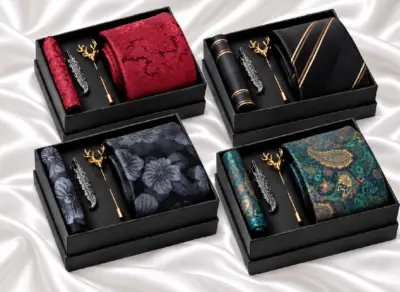 Four boxed tie sets featuring burgundy paisley, black and gold stripes, grey floral and teal paisley designs